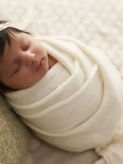 The perfect "Hello World" announcement. This classic newborn photo shows a peacefully sleeping baby swaddled snugly in a soft white blanket, looking pure and angelic.