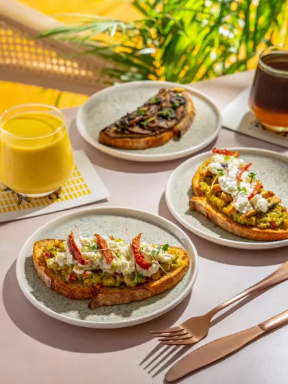 A wider shot of the brunch spread at Blue Tokai, including their signature coffee. The natural light and fresh ingredients create a very appealing and wholesome image.