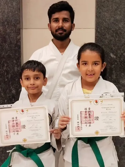 Hard work pays off. These two students proudly display their new green belt certificates, a significant milestone in their karate training that reflects their growing skill and discipline.