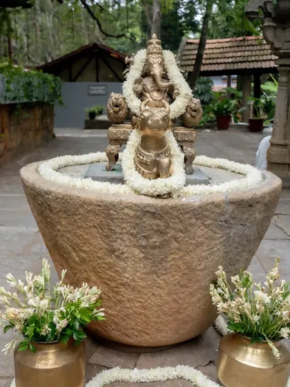 A Ganesha idol placed in a large stone urli, creating a powerful and auspicious focal point.