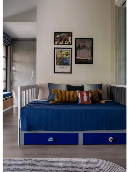 A feature on the son's room, showing a daybed with smart storage drawers in a bold blue. The gallery wall above adds a personal and artistic touch to this functional and stylish space.