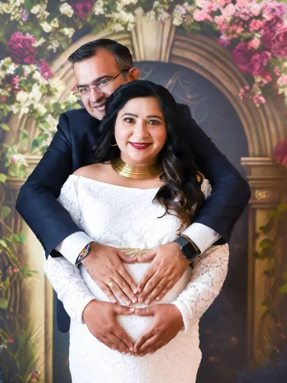 A beautiful couple's portrait in our studio, with the dad-to-be lovingly embracing his partner from behind.