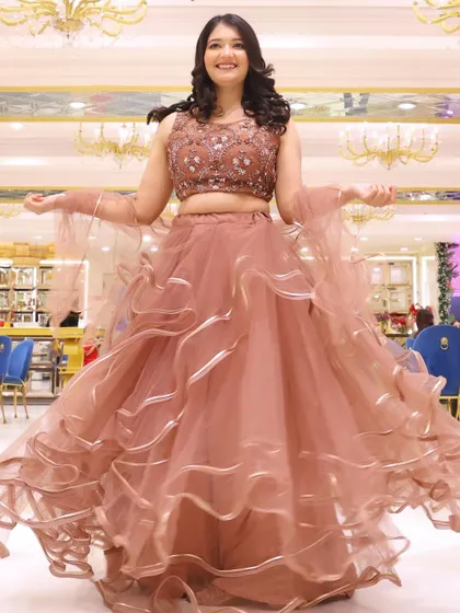 A fun, twirling shot in a beautiful dusty rose lehenga with a ruffled skirt. The makeup is soft and pretty, perfect for a daytime event.