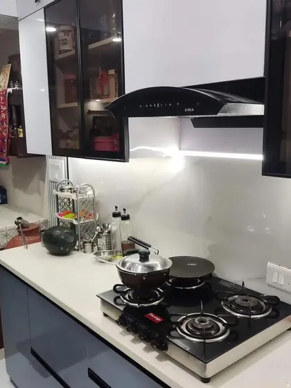 Here you can see the placement of the Kaff chimney and the hob, along with the under-cabinet lighting that illuminates the entire cooking area. The combination of white and blue with glass-front cabinets creates a balanced and airy feel.