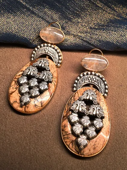 A unique pair of earrings combining earthy brown stone with intricate silver work, creating a rustic yet elegant piece.