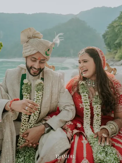 Laughter and love by the Ganga. This candid photo captures the genuine joy of the couple, with the bride's natural makeup looking fresh and beautiful throughout the ceremony.