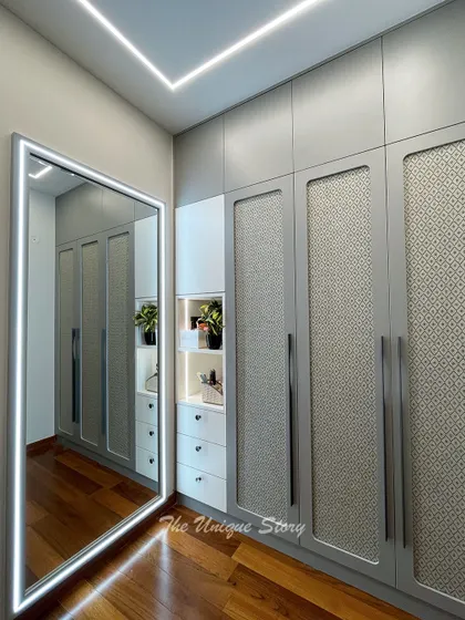 A custom wardrobe solution featuring rattan-paneled doors in a Duco finish. The design includes a full-length mirror with integrated LED lighting, combining functionality with a touch of modern-bohemian style.
