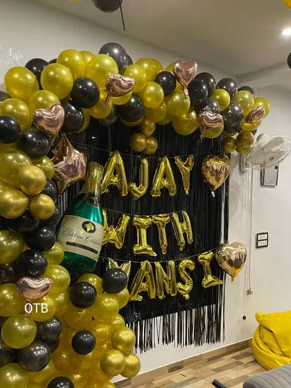 Make it personal with custom name foil balloons. This fun anniversary backdrop uses a black and gold theme with a champagne bottle balloon to celebrate the happy couple, Ajay and Mansi.