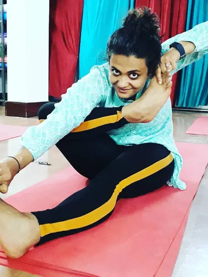 A student in Akarna Dhanurasana (Archer's Pose), which improves hip flexibility and concentration. This pose demonstrates the level of dedication our students achieve.