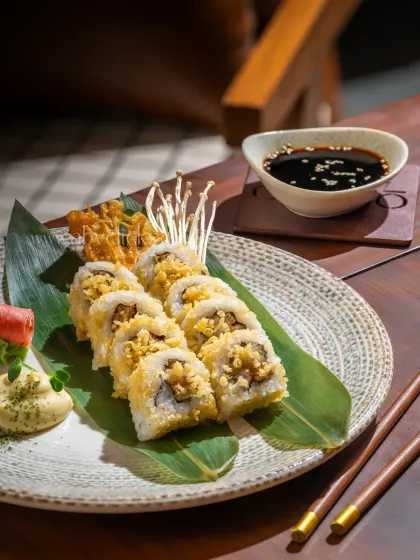 A platter of crunchy tempura sushi rolls, garnished with enoki mushrooms and served with wasabi and soy sauce.