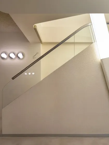 The minimalist staircase design, with a glass balustrade and integrated lighting, feels both light and solid.