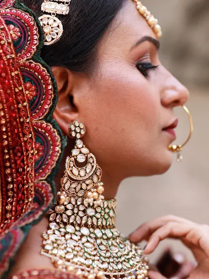 A detailed shot of the bride's profile, showcasing her stunning earring, makeup, and the intricate design of her headpiece.