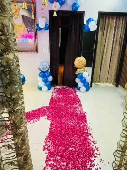 A home entrance decorated with a rose petal pathway and 'Baby Boy' balloon pillars.