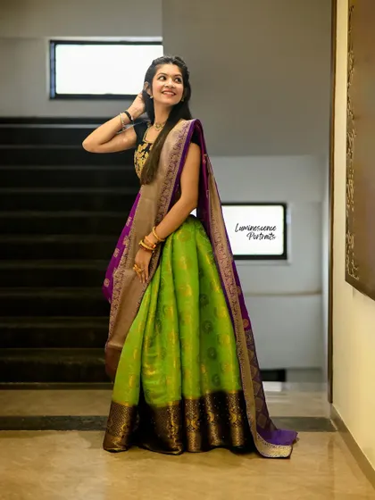 A vibrant half-saree in parrot green and royal purple, draped elegantly for a modern traditional look. This shot captures the full, flowing silhouette.