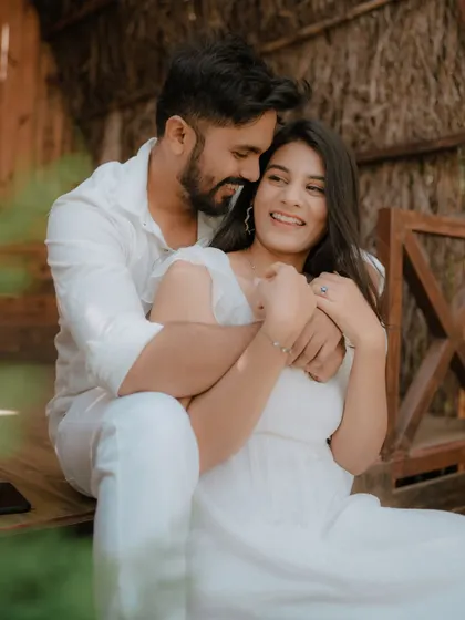A moment of pure, uninhibited laughter on a rustic wooden porch. Dressed in coordinated white, this couple's joy is infectious, showcasing a perfectly candid moment from their pre-wedding shoot.