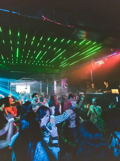 A wide shot of the club, showing people dancing under green and red ceiling lights. It gives a great sense of the venue's atmosphere.