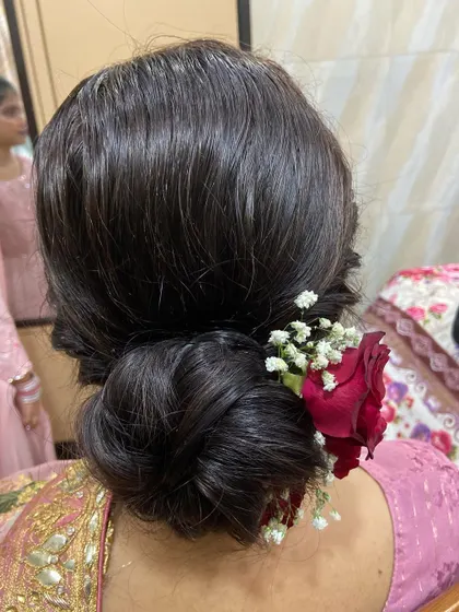 A simple yet elegant low bun adorned with a few red roses and baby's breath for a subtle touch of color.