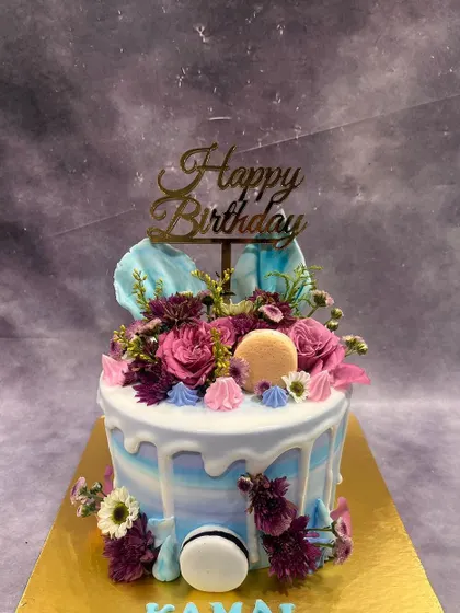 A burst of floral beauty on this drip cake. We topped it with fresh flowers, macarons, and meringue kisses for a design that is both colorful and delicious.