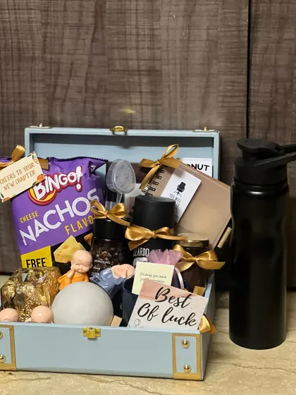 A farewell gift hamper curated for a departing team member. It includes a mix of fun snacks, a water bottle, and quirky items to wish them well on their next chapter.