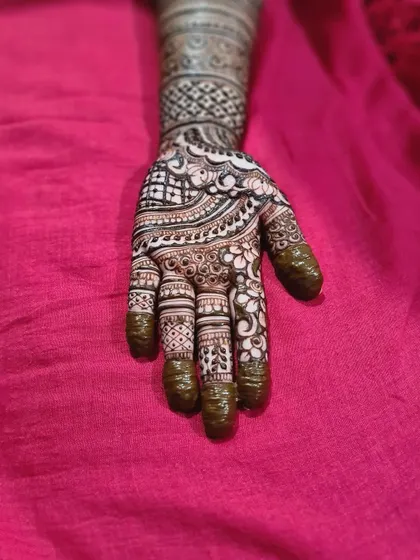 A beautiful henna design for a baby shower, featuring intricate patterns on the hand and a clean, banded design on the arm.