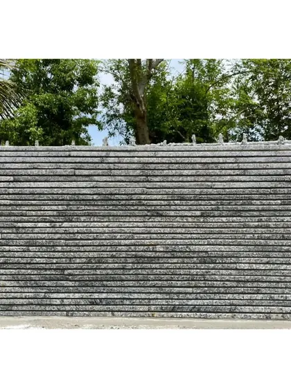 The finished texture of the Nandi House wall, built from waste granite off-cuts. The horizontal lines create a strong graphic quality against the lush green landscape.