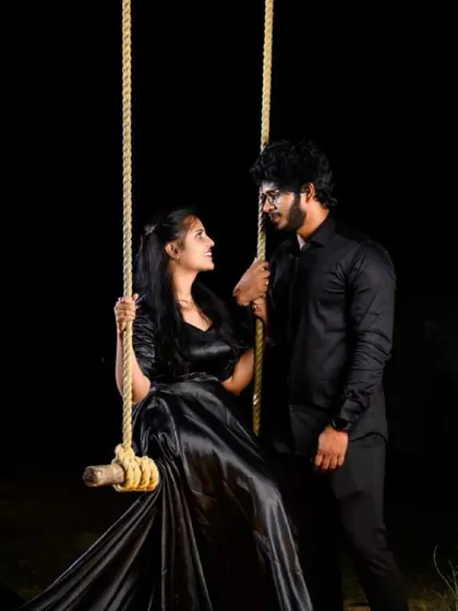An intimate moment from a pre-wedding shoot. The couple is dressed in matching black satin outfits, creating a sleek and romantic look perfect for night photography.