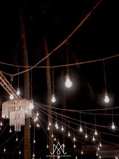 A canopy of hanging bulbs and a crystal chandelier create a magical, starry night effect over the dinner tables.