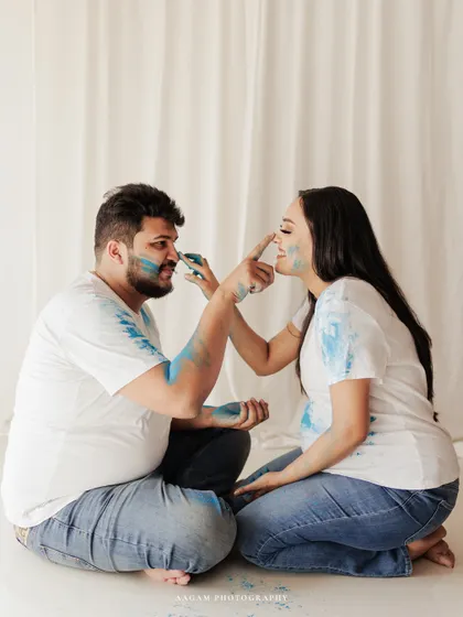 A playful gender reveal moment during a maternity session, with blue powder adding a splash of fun and excitement to the portraits.