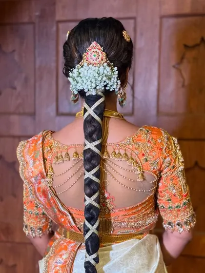 A modern take on the traditional braid, this style features a criss-cross pattern using a ribbon. It's adorned with a beautiful floral and jewel piece at the top, perfect for a contemporary bride.