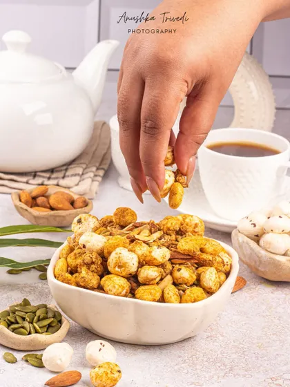 A bowl of healthy makhana (fox nut) mix, styled with a cup of tea for a perfect evening snack shot.
