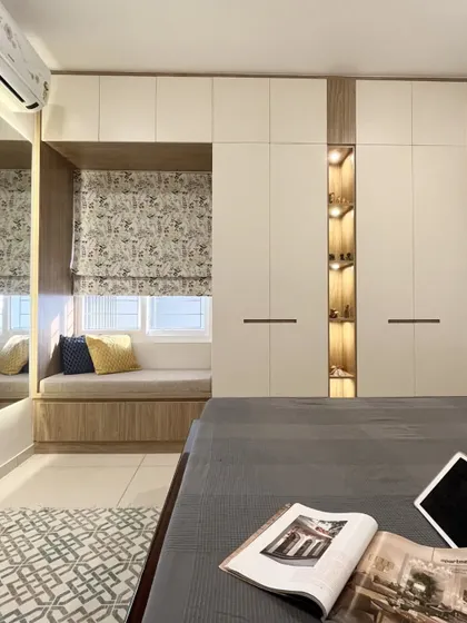 A bay window seat integrated into a full wall of wardrobes. This design is a perfect example of maximizing storage while creating a comfortable nook.