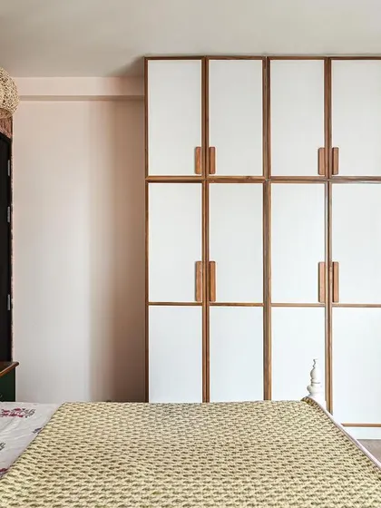 A full view of the guest room, showing how the white wardrobe with teak details balances the bold, patterned wallpaper.