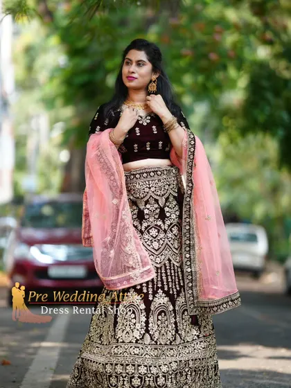 A dark velvet lehenga with intricate gold embroidery, paired with a soft pink dupatta. The contrast is elegant and eye-catching.