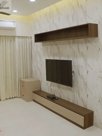 A second living area in the Ayyapakkam villa, with a simple floating TV unit set against a full-wall marble-finish panel for a clean and luxurious feel.