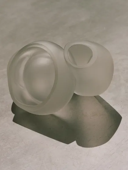 A still life of two frosted glass pendants from the Bocci 100 series, their soft, sculptural forms highlighted by the play of light and shadow.