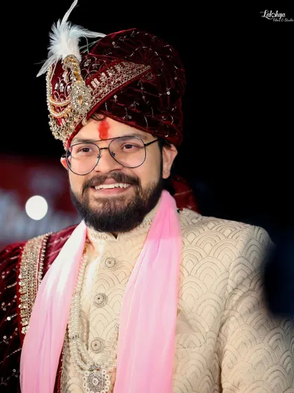 A close-up portrait of the smiling groom. This shot perfectly captures his happiness and the fine details of his wedding turban (safa).
