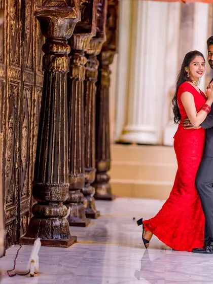 A romantic pose in a corridor of wooden pillars. The bride's red dress adds a beautiful pop of color to this classic, elegant setting.