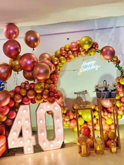 An indoor 40th birthday celebration with a circular balloon arch in metallic tones and large marquee numbers.