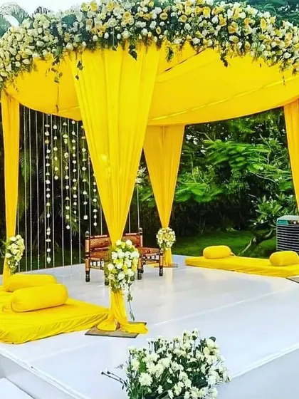 A modern and sunny Haldi mandap. The circular yellow canopy and clean white stage create a chic and stylish setting for a daytime ceremony.