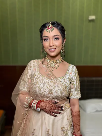 The final look for this bride in her ivory lehenga. The makeup is soft glam, with a focus on defined eyes and a neutral lip.