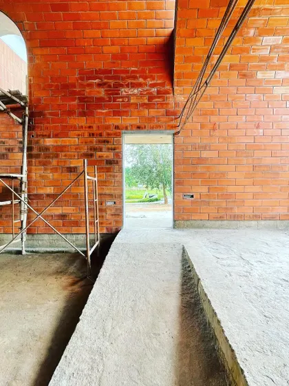 A view through a doorway in the 'Vault & Wall' house, where the rich red of the hollow clay bricks is the primary finish. The ramp provides accessible circulation through the space.