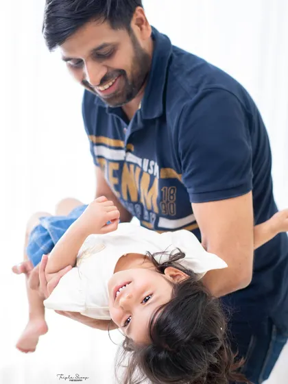 A father playfully holds his daughter upside down, both of them laughing. Capturing these fun, energetic moments is key to a memorable family session.