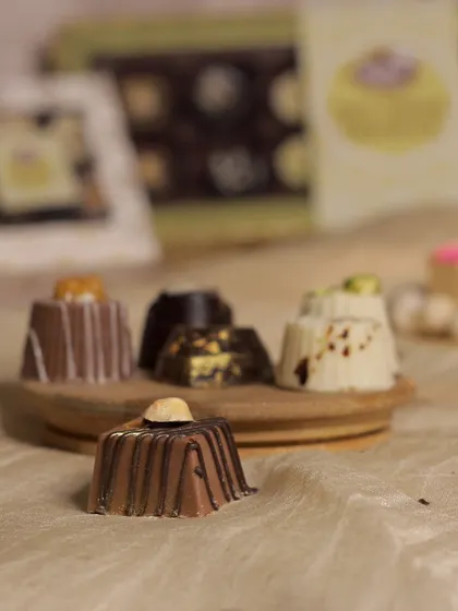 A close-up of our hazelnut soft-centered chocolate. This piece features a whole hazelnut on top and a rich, creamy filling inside a milk chocolate shell.