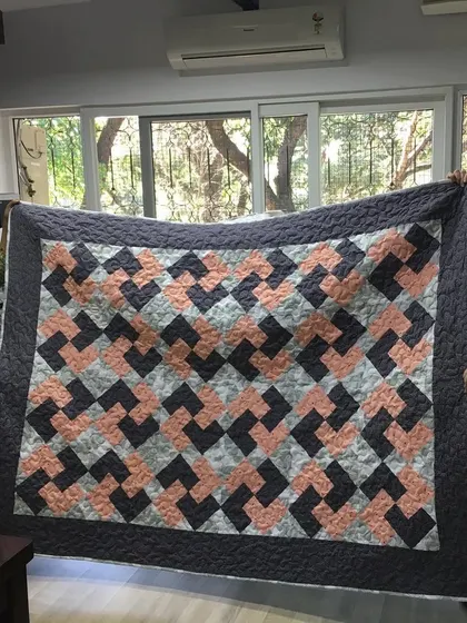 Two of our happy clients holding up a finished "Chinese Coins" or "Rail Fence" patterned quilt.