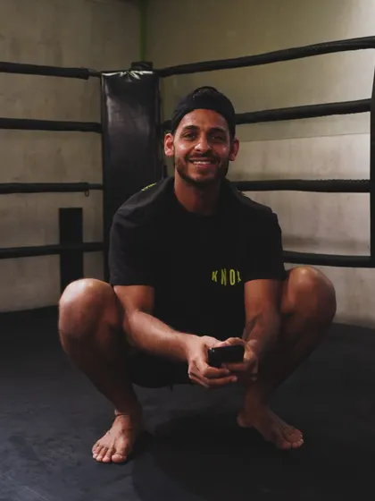 A coach smiles while relaxing in the boxing ring. Our team is approachable, friendly, and a core part of the Knox community.