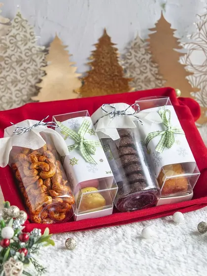 Our Christmas hampers offer a symphony of flavors. This one includes spiced cashews, assorted cookies, and small cakes, presented in festive packaging perfect for sharing the joy of the season.
