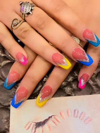 A bold and colorful design with multi-colored V-tips in blue, yellow, and pink. The look is enhanced with a thick line of silver glitter separating the color from the nude base.