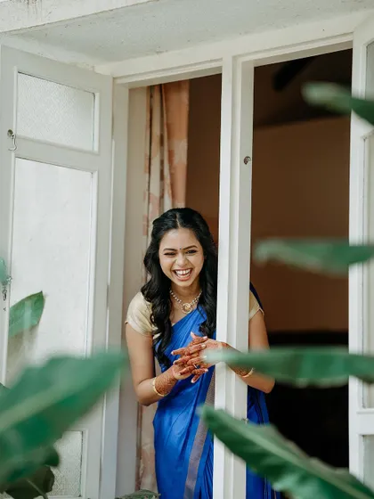 A candid shot of the bride laughing while peeking out of a window, her joy is infectious.