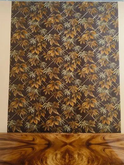 A dark wallpaper with a golden leaf trellis pattern, used as an accent piece above a wooden console. The rich colors create a luxurious and elegant focal point.