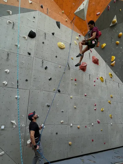 A climber takes a rest mid route while his partner belays him from below. Trust between a climber and their belayer is the foundation of safe lead climbing.